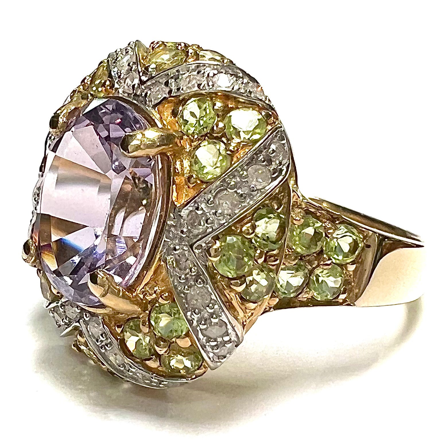 A ladies' yellow gold ring set with an oval cut lavender spinel center stone and diamond and peridot accent stones.