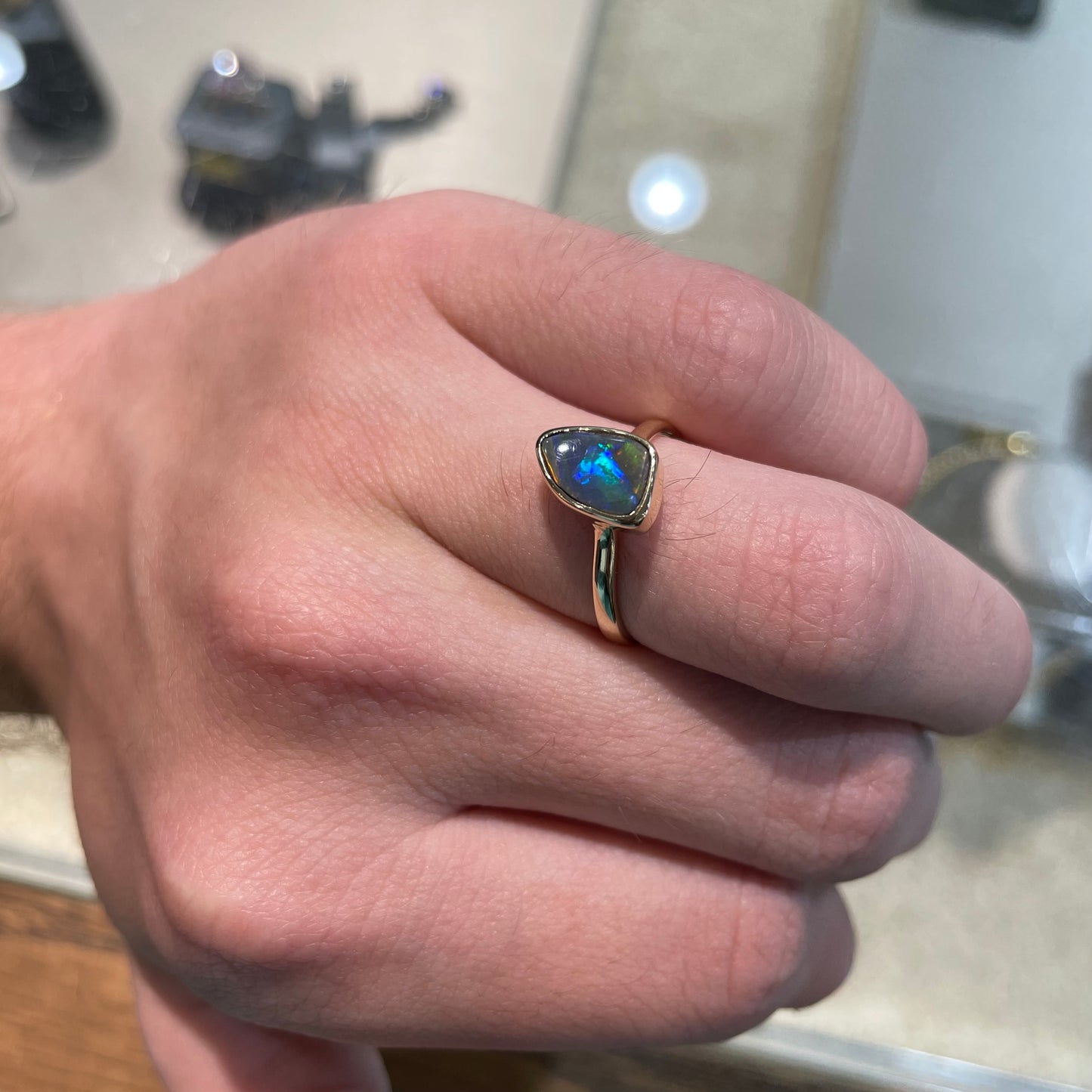 A handmade yellow gold solitaire ring bezel set with a Lightning Ridge red-on-black harlequin opal.