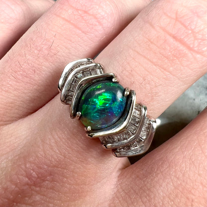 A white gold ring set with a Lightning Ridge black opal and baguette cut diamonds.