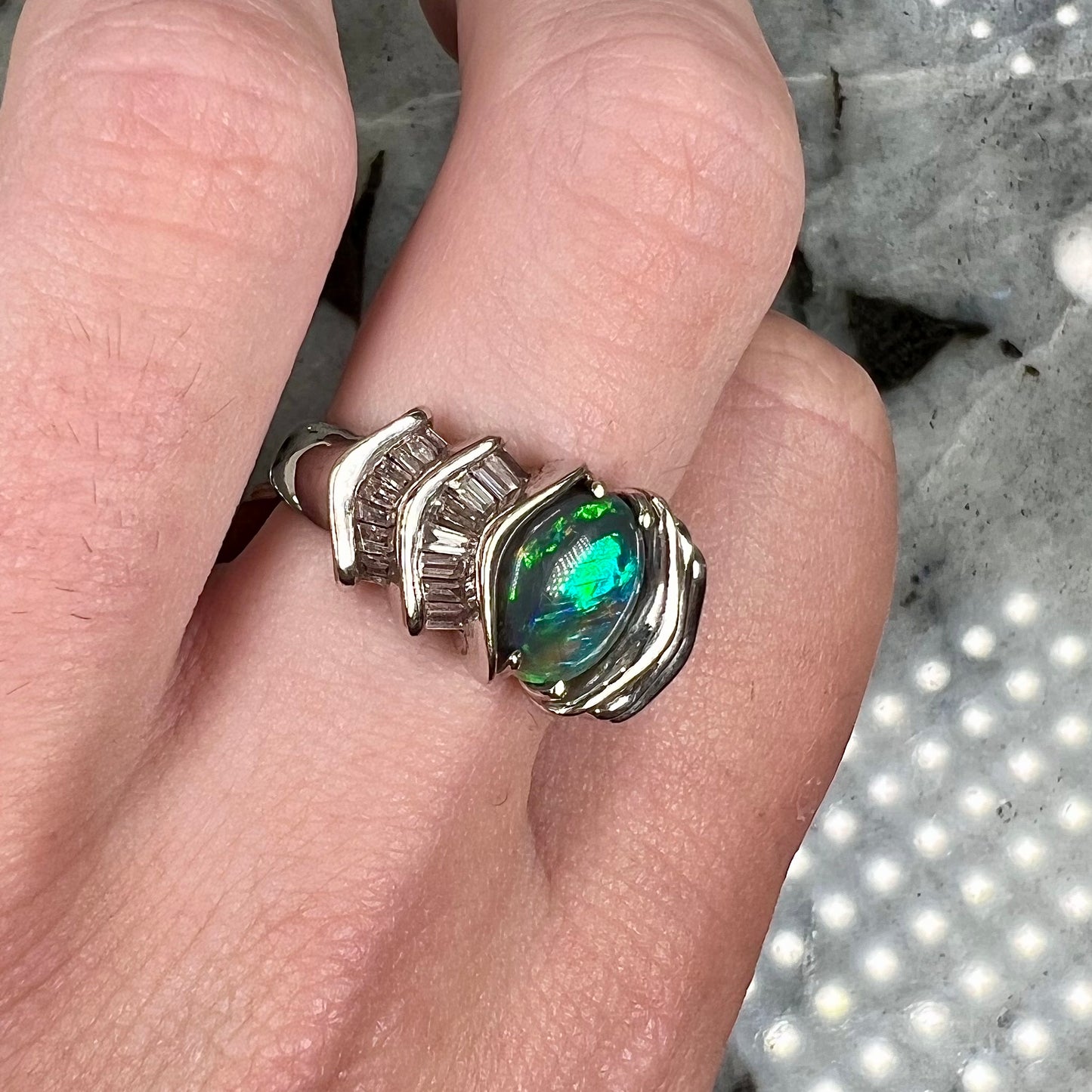 A white gold ring set with a Lightning Ridge black opal and baguette cut diamonds.