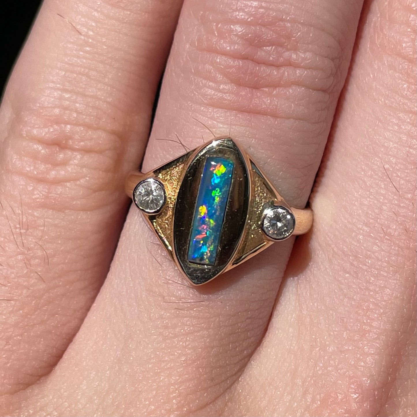 Lightning Ridge black opal set between two round diamonds in an 18 karat yellow gold ring. Anaheim, California.