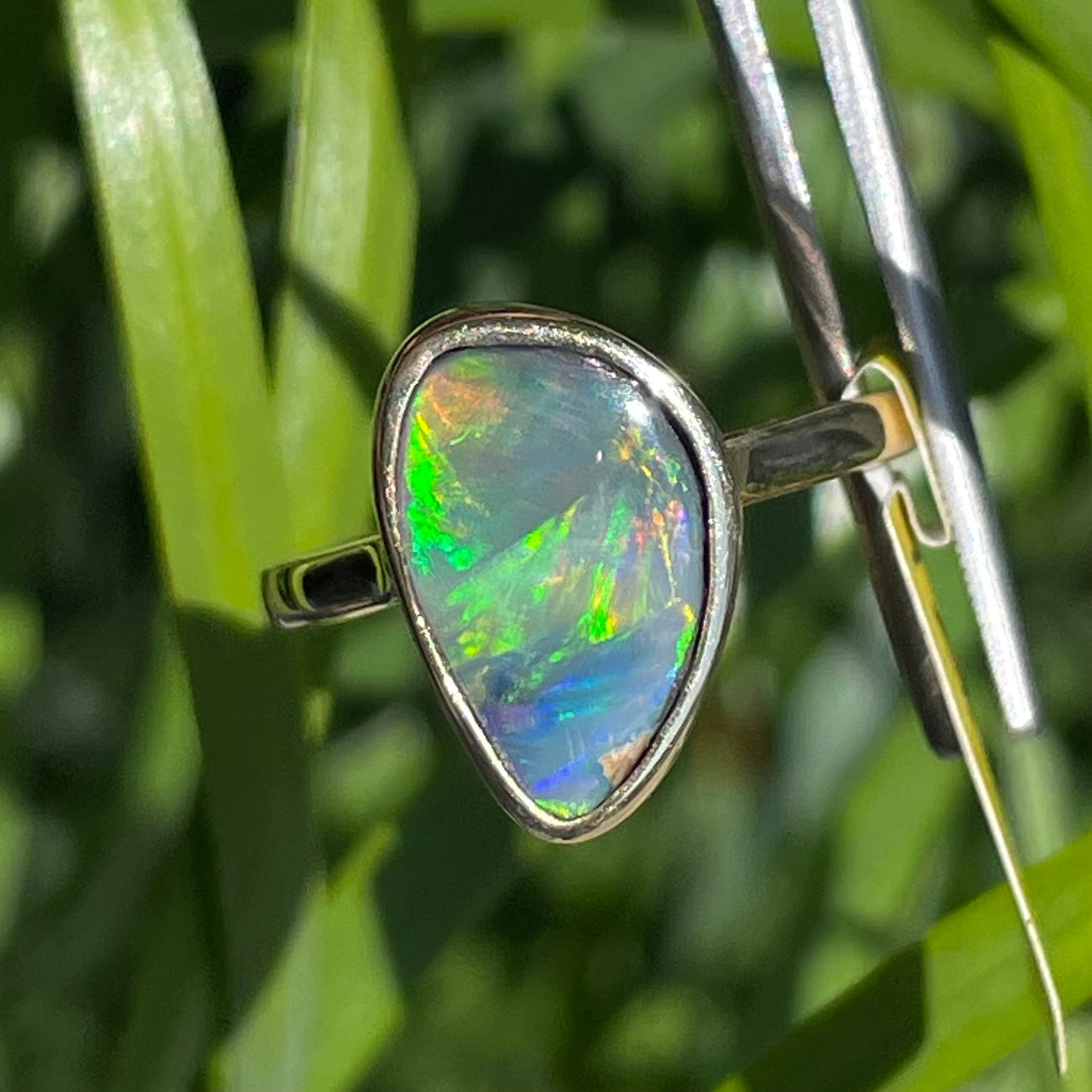 A freeform cut semi-black opal from Lightning Ridge, Australia set in a bezel set yellow gold solitaire ring.