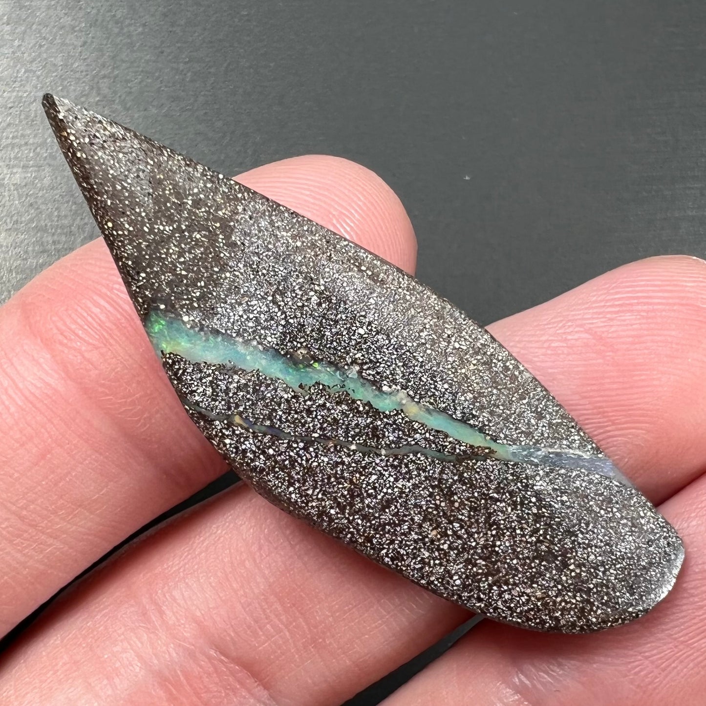A loose Quilpie boulder opal stone. The stone is blue and has a bright rainbow tip.