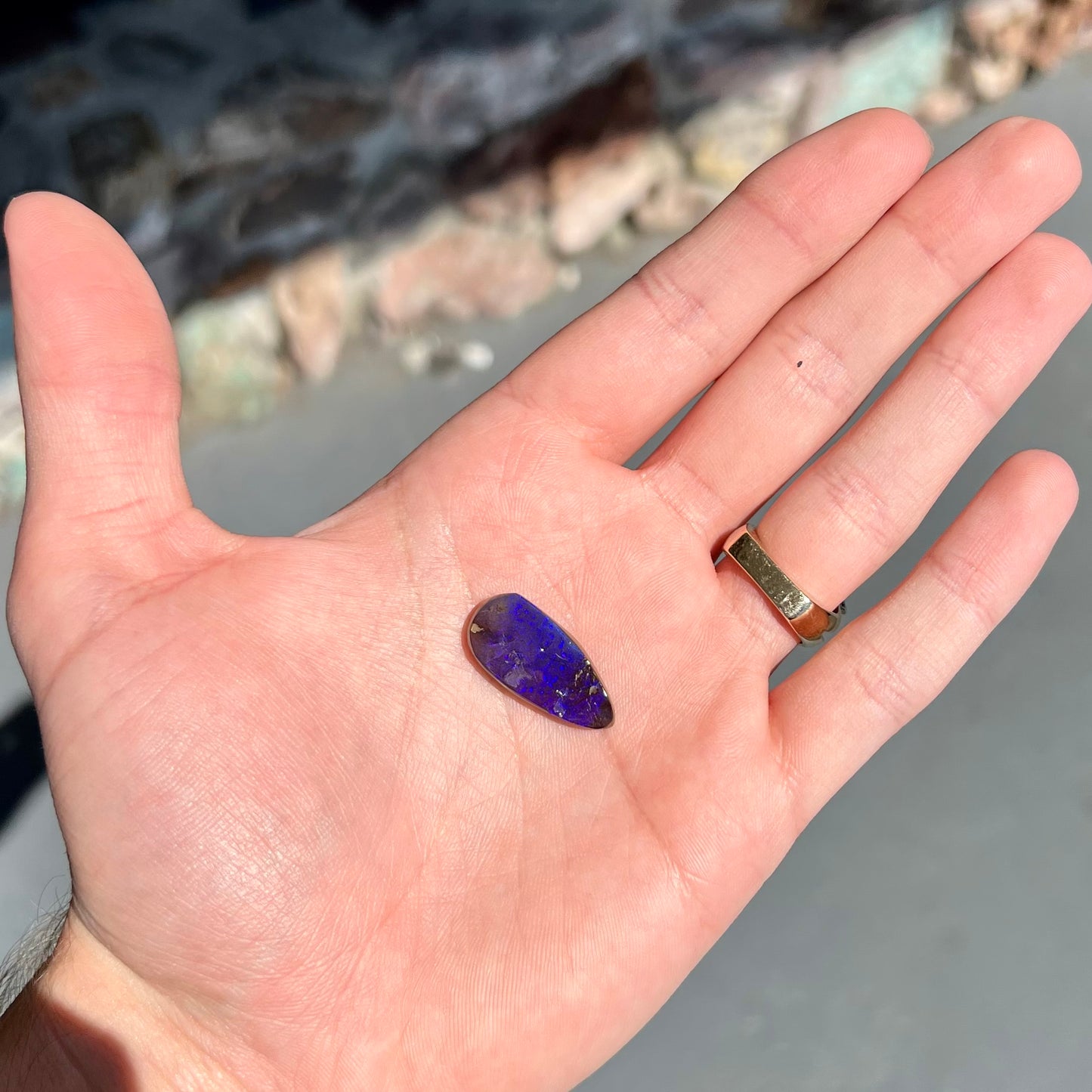 A loose, teardrop shaped purple boulder opal stone.