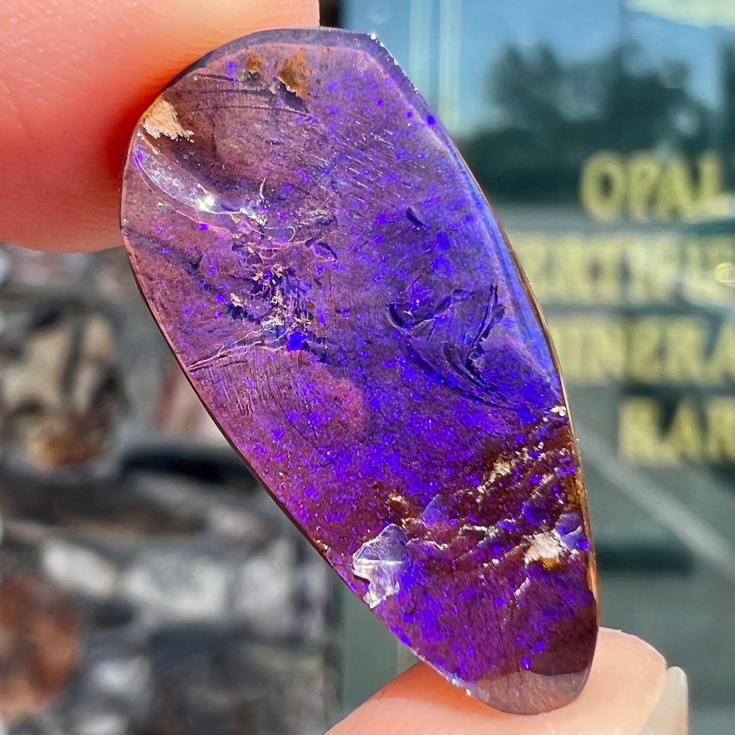 A loose, teardrop shaped purple boulder opal stone.