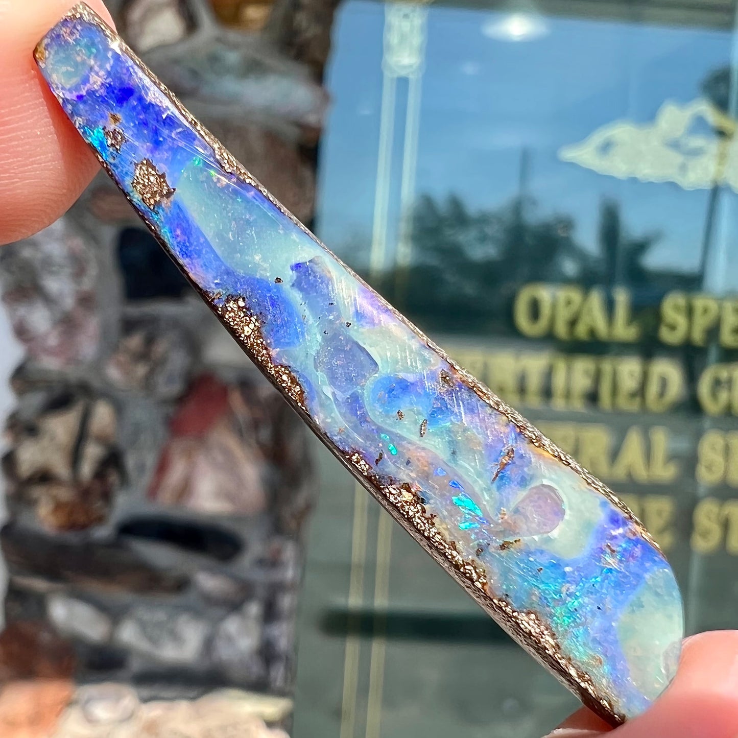 A loose, polished Quilpie boulder opal stone from Australia. The stone is predominantly blue.