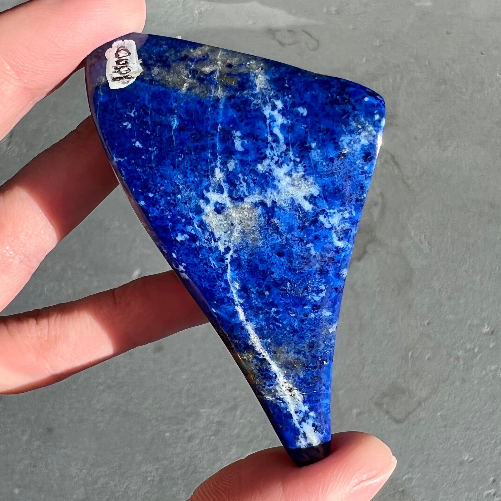 A loose polished sculpture made from royal blue lapis lazuli with golden pyrite inclusions.