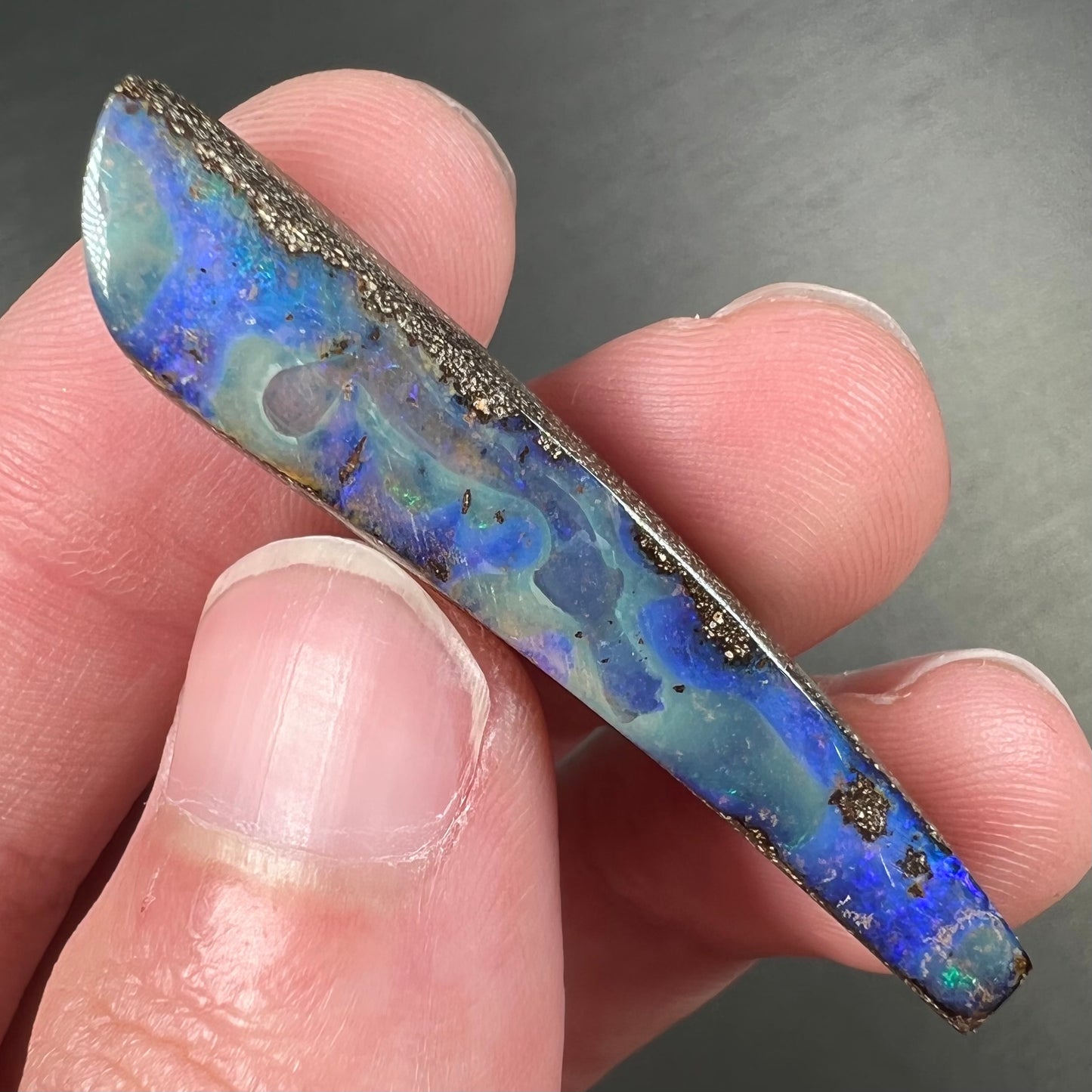 A loose, polished Quilpie boulder opal stone from Australia. The stone is predominantly blue.