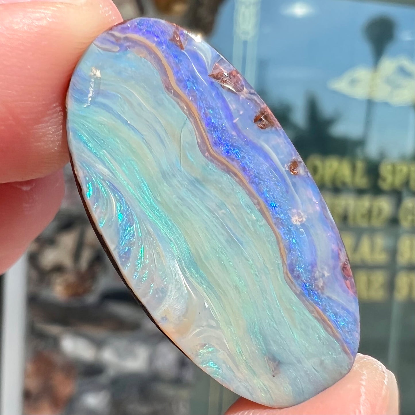 A loose, oval cabochon cut boulder opal stone from Queensland, Australia.