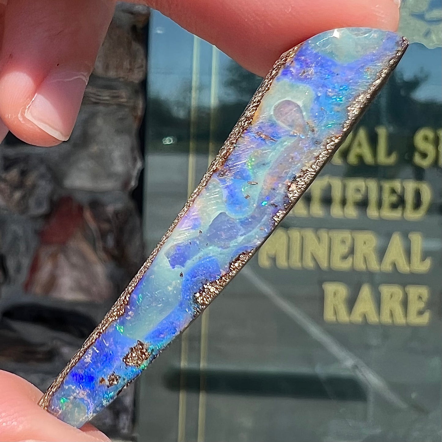 A loose, polished Quilpie boulder opal stone from Australia. The stone is predominantly blue.