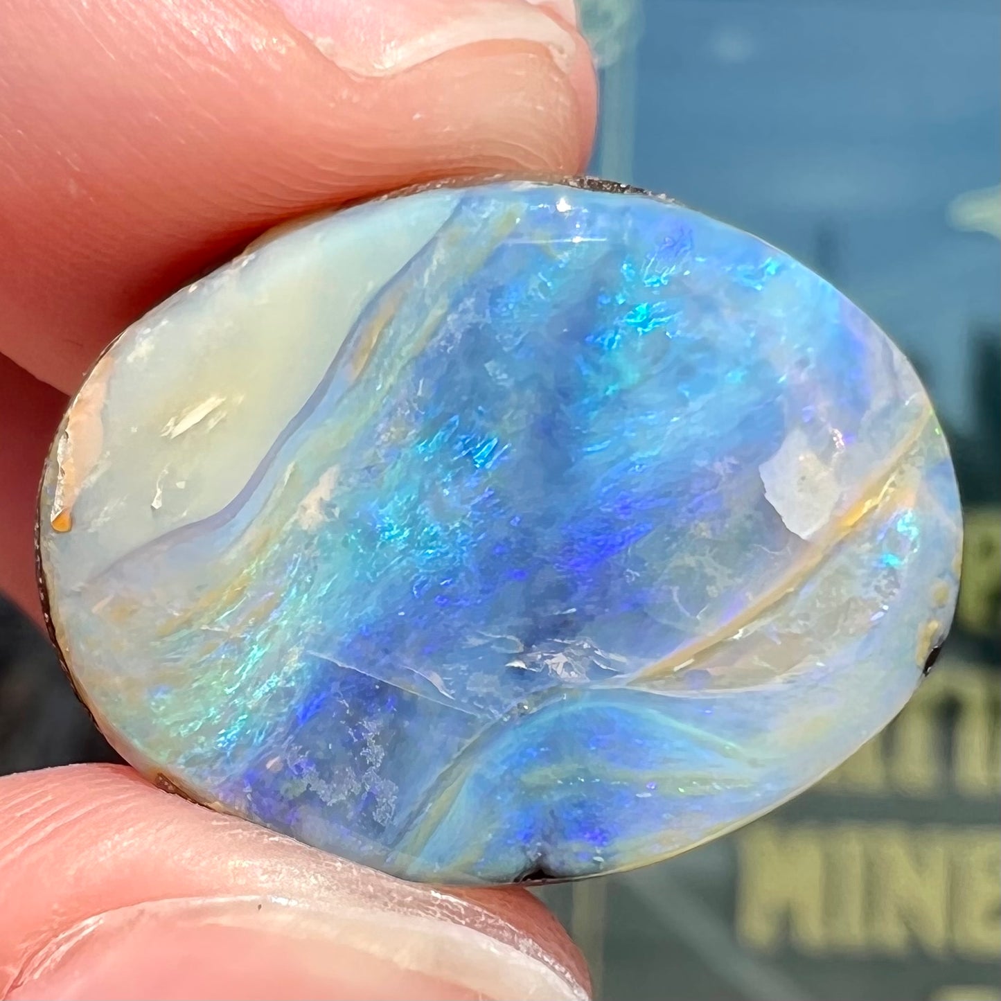 A loose, oval cabochon cut Australian boulder opal stone.