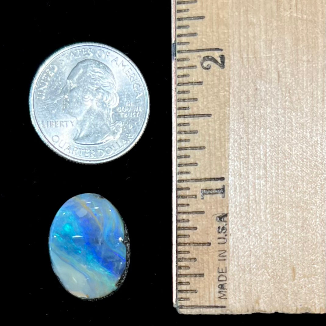 A loose, oval cabochon cut Australian boulder opal stone.