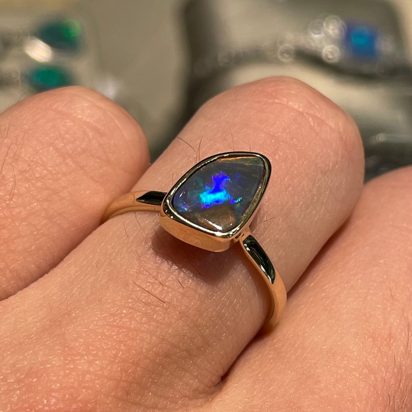A handmade yellow gold solitaire ring bezel set with a Lightning Ridge red-on-black harlequin opal.