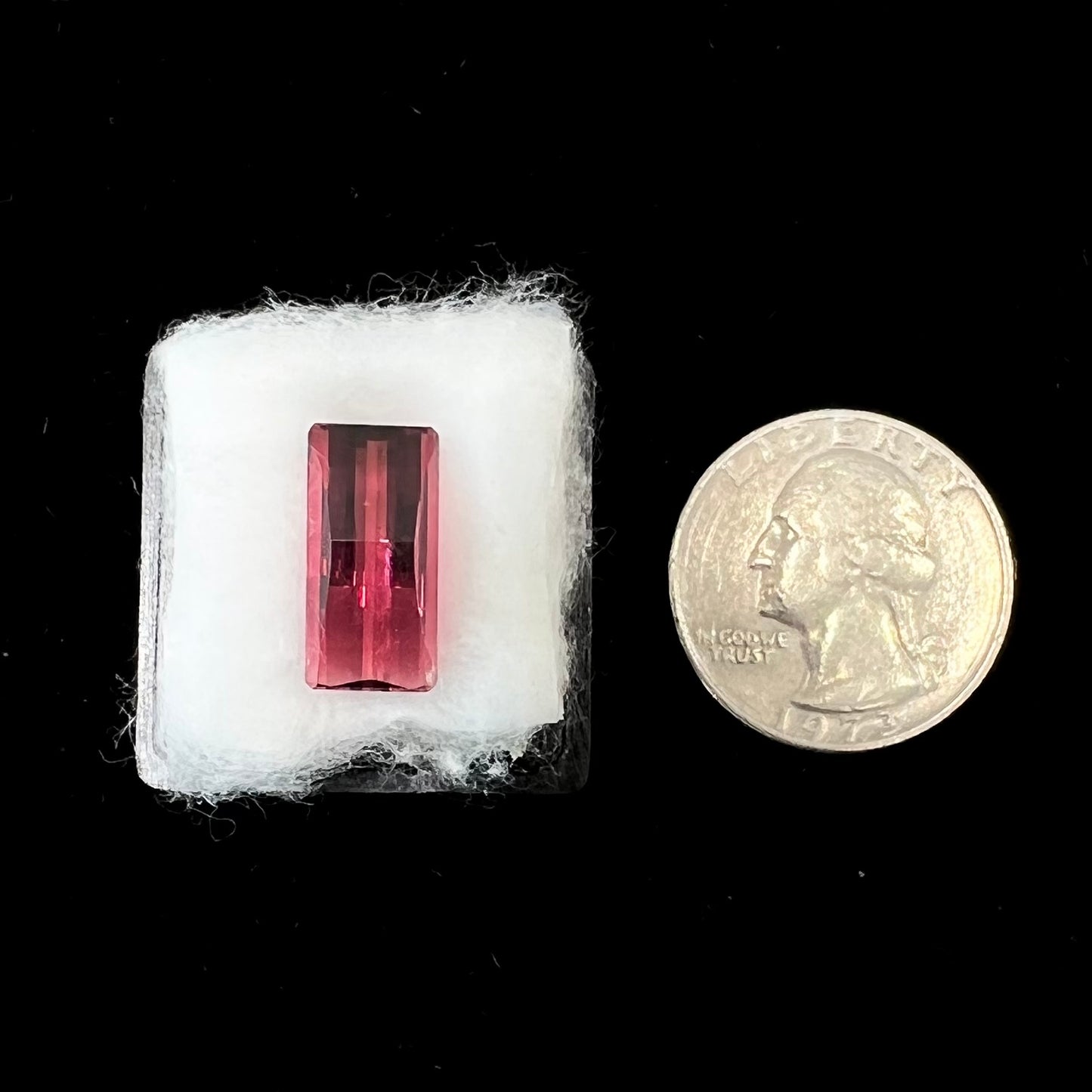 A loose, fantasy cut reddish colored tourmaline. The cut reflects light in a way that resembles digital pixels on a screen.