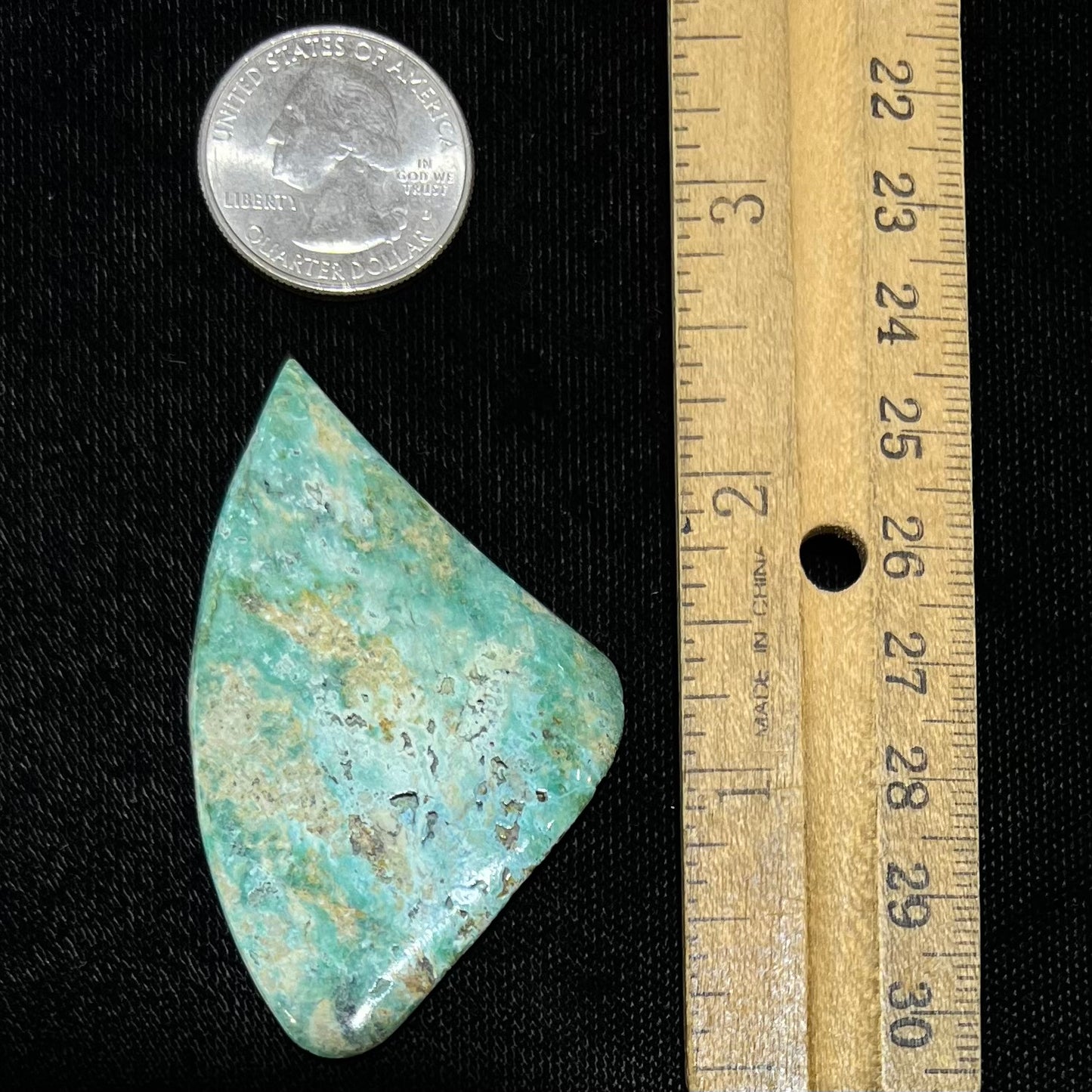 A triangular cut polished green turquoise stone from Morenci, Arizona.
