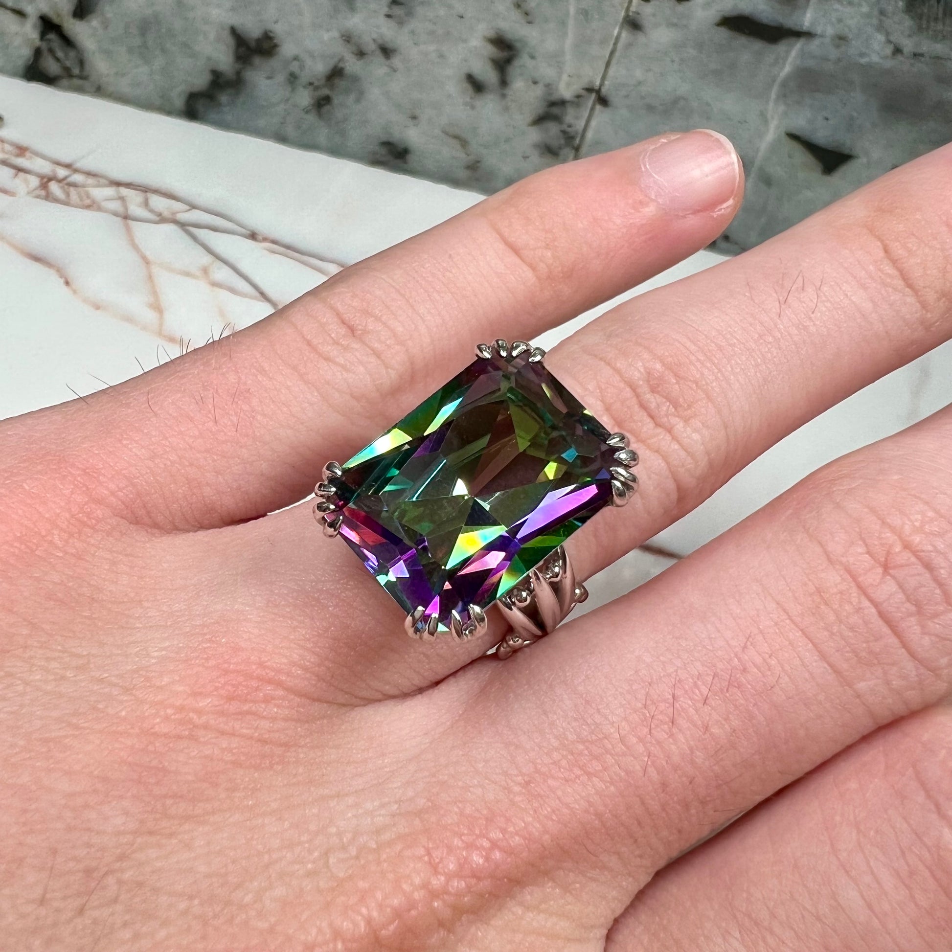 Emerald cut mystic topaz prong set in a decorative sterling silver ring.