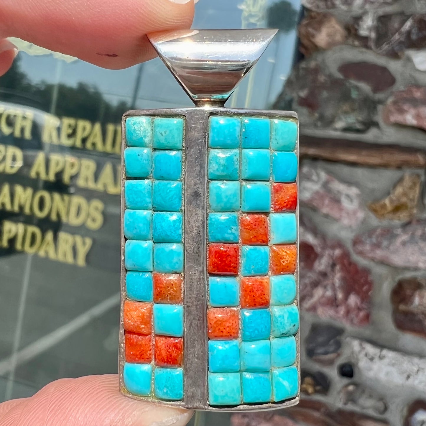 A silver pendant set with square cabochon cut turquoise and coral stones. The piece is stamped "DTR CHINA".