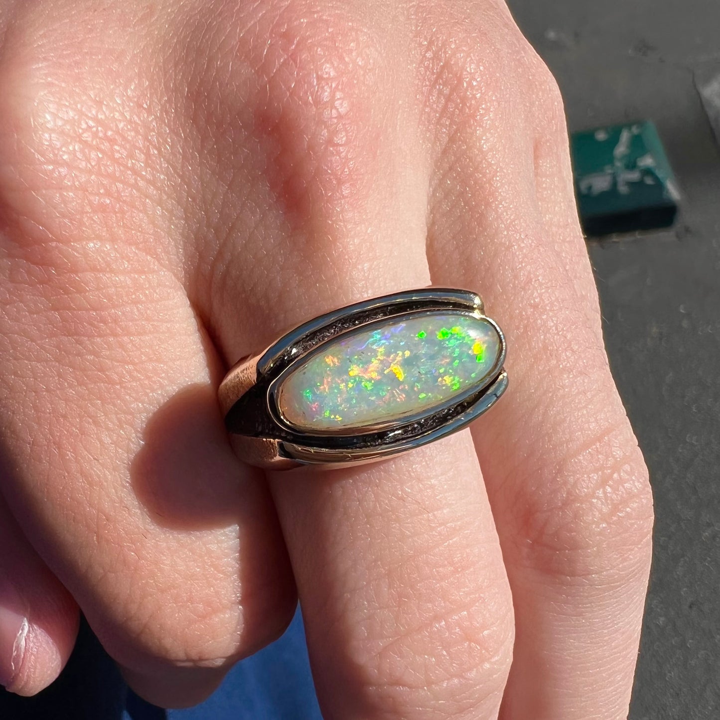 An Australian white crystal opal men's ring in solid yellow gold. The recesses of the ring have been blackened.