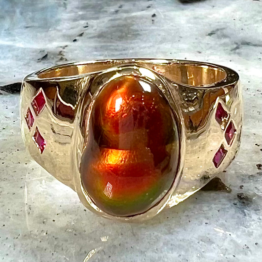 A yellow gold men's ring set with princess cut Burma rubies and a freeform cabochon cut red fire agate from Slaughter Mountain, Arizona.