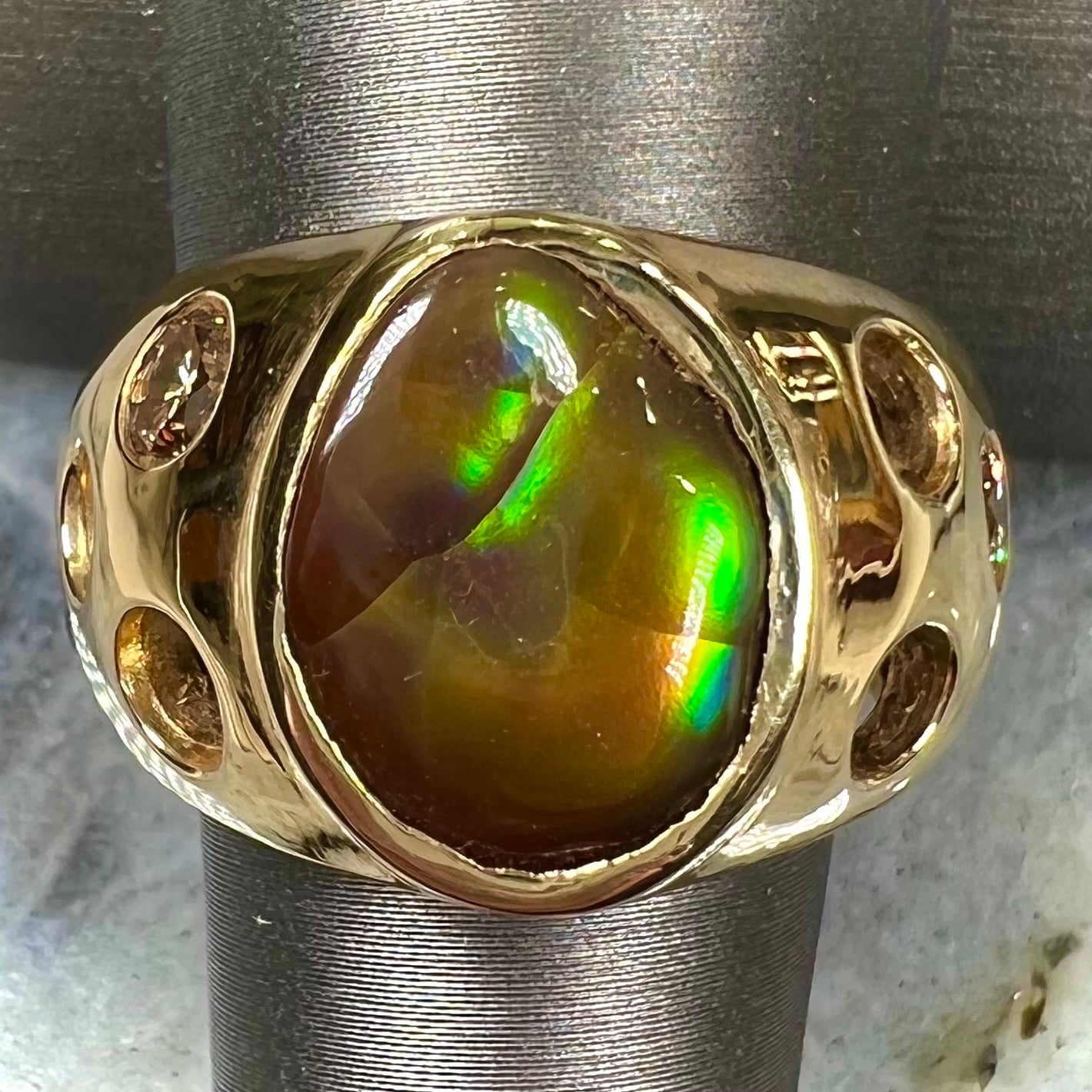 Men's rainbow fire agate ring set in yellow gold with champagne diamonds. The ring style has holes.