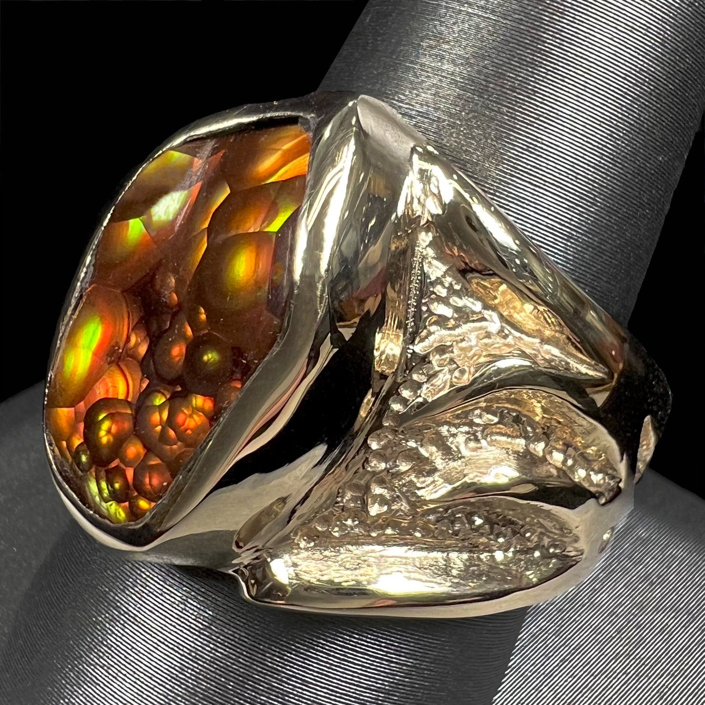 A men's yellow gold fire agate solitaire ring. The stone has a botryoidal pattern with sagenite inclusions.