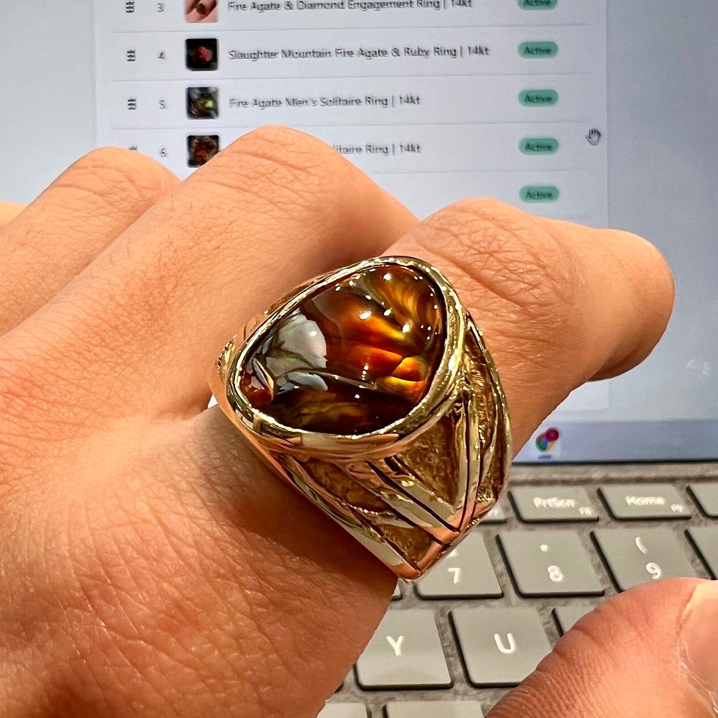 A solid, yellow gold men's fire agate ring. The predominant color is red with green undertones.