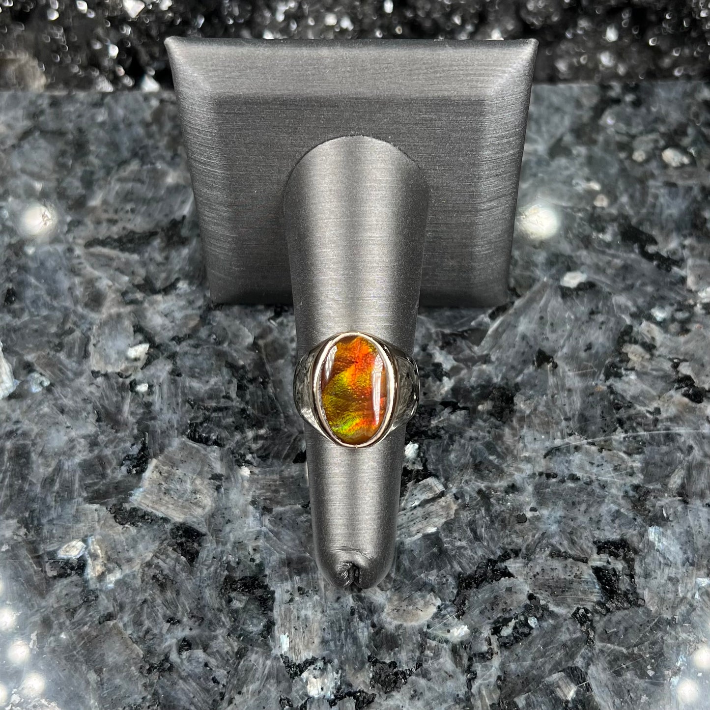 A yellow gold solitaire fire agate men's ring. The fire agate is oval shape, and red and green in color.