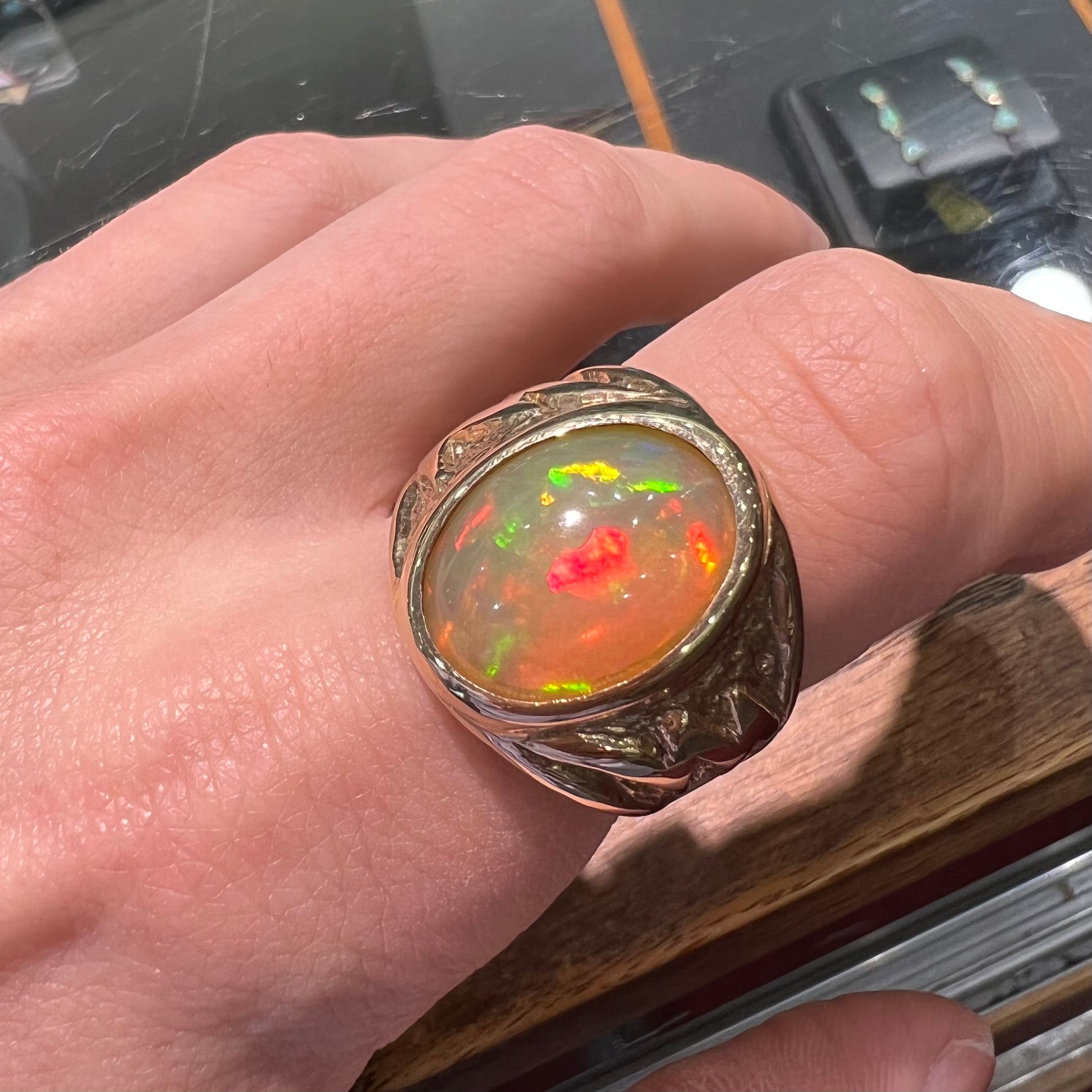 A solid yellow gold solitaire men's fire opal ring.  The stone is an orange oval cabochon cut.