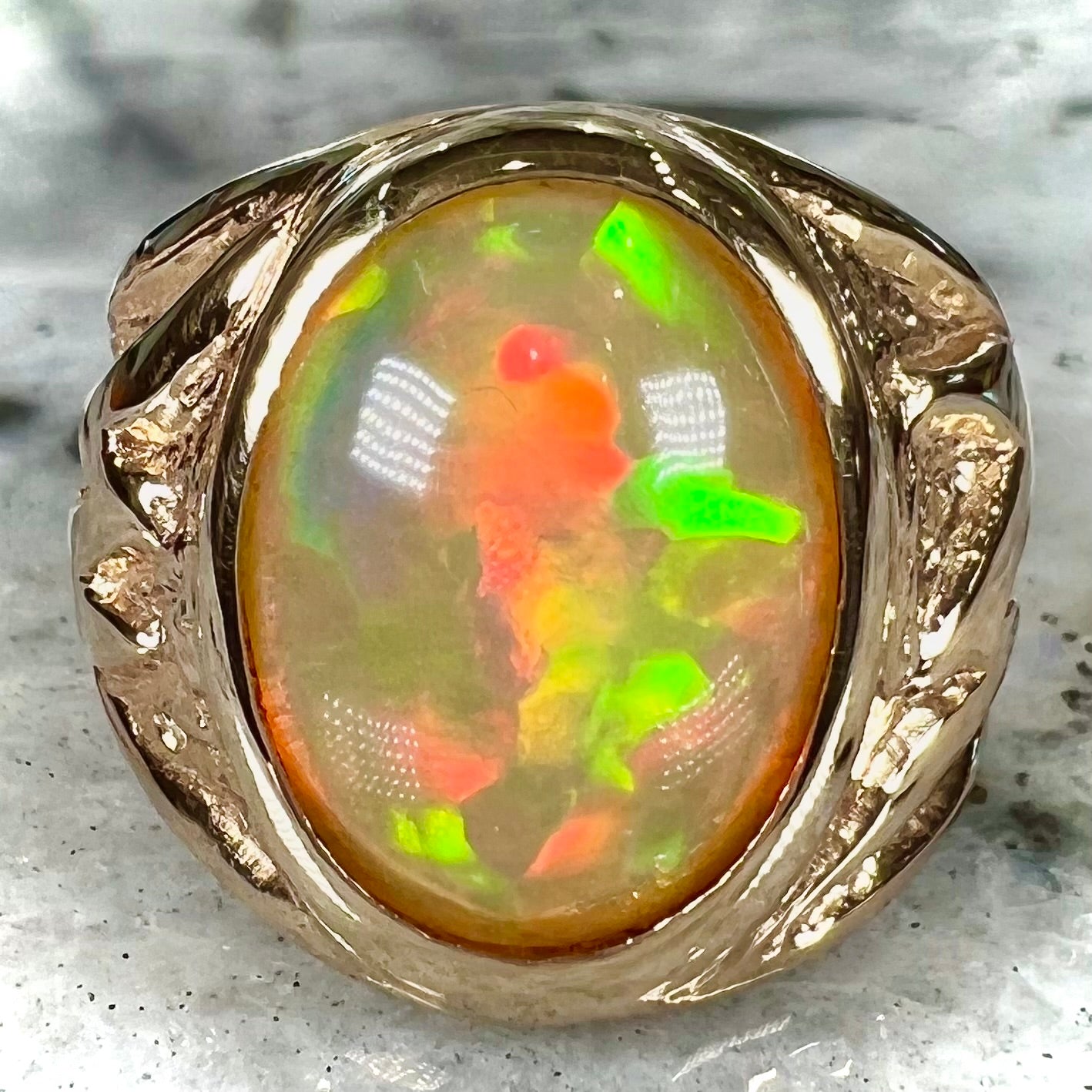 A solid yellow gold solitaire men's fire opal ring.  The stone is an orange oval cabochon cut.