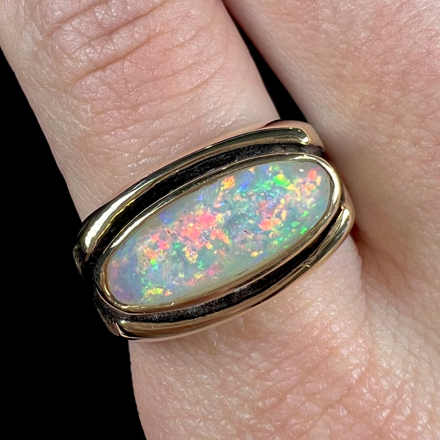 An Australian white crystal opal men's ring in solid yellow gold. The recesses of the ring have been blackened.