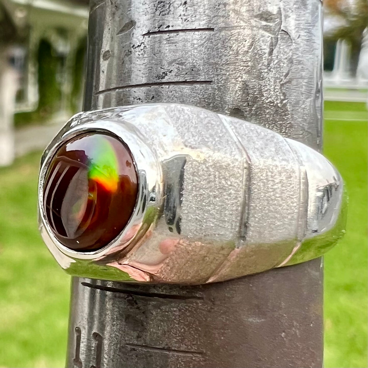 A round cabochon cut red and green fire agate set in a brushed metal white gold men's ring.