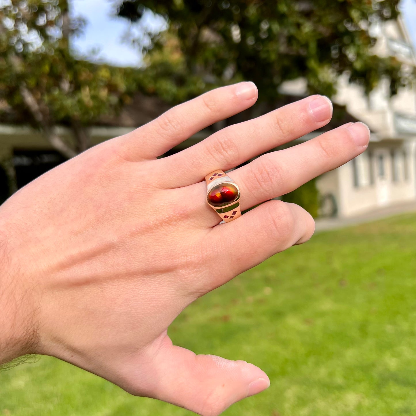 A yellow gold men's ring set with princess cut Burma rubies and a freeform cabochon cut red fire agate from Slaughter Mountain, Arizona.