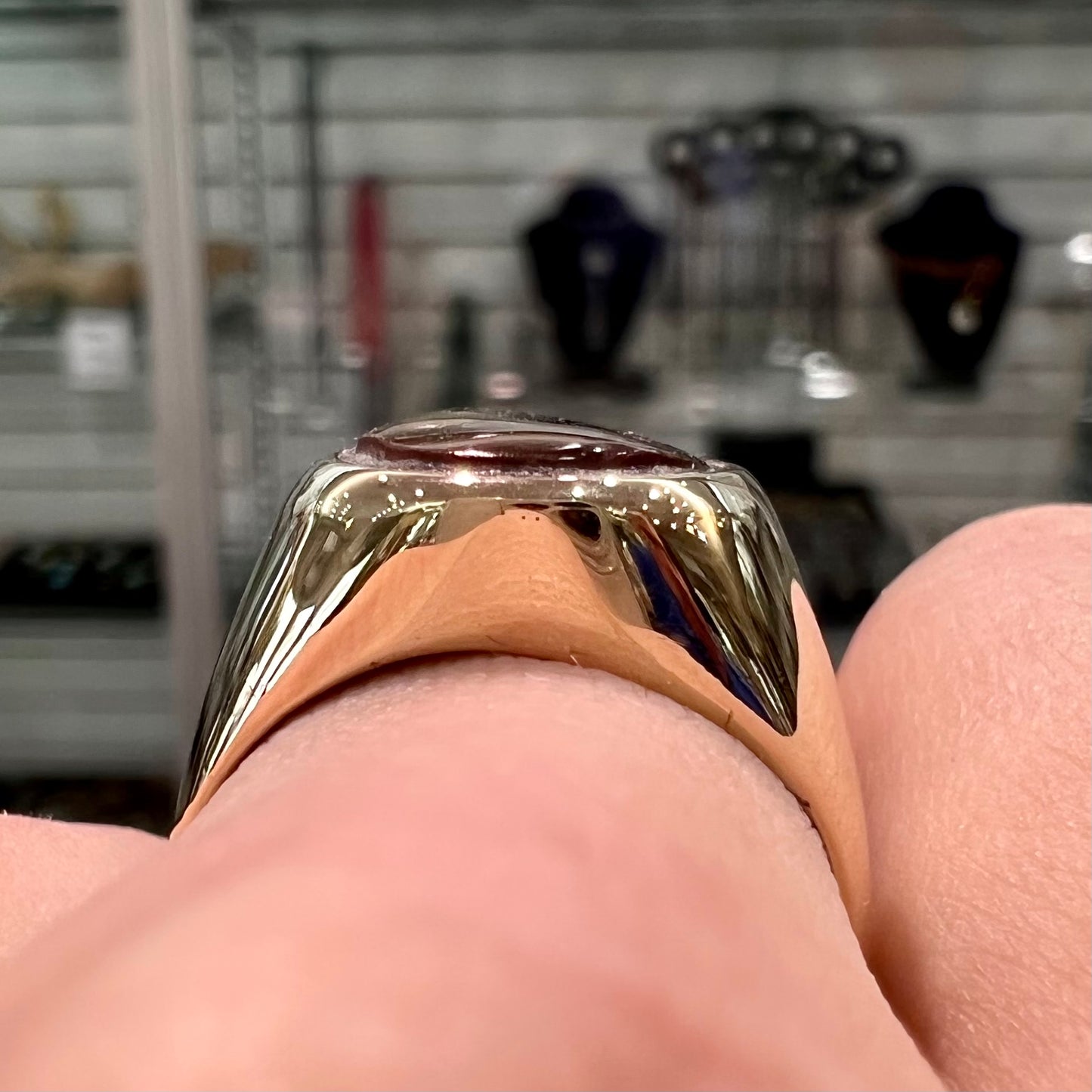 A yellow gold solitaire fire agate men's ring. The fire agate is oval shape, and red and green in color.