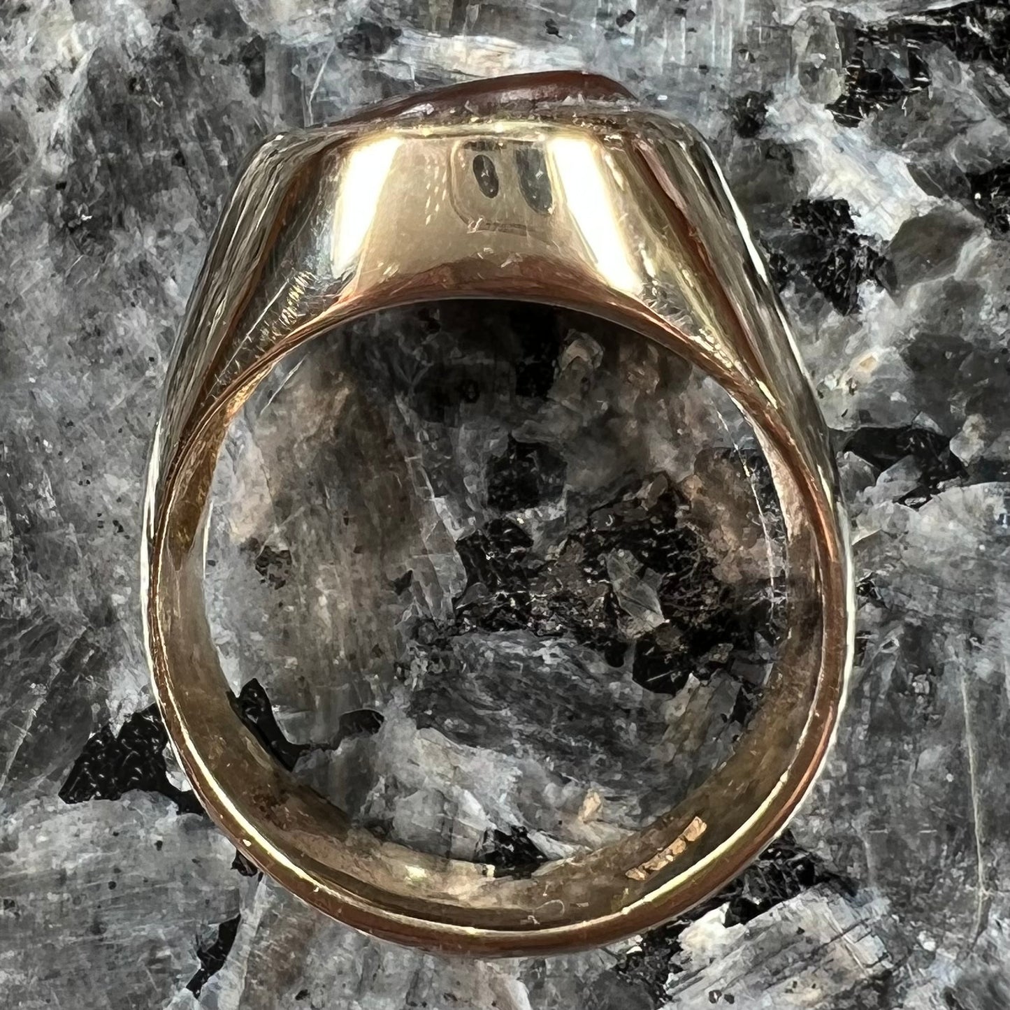 A yellow gold solitaire fire agate men's ring. The fire agate is oval shape, and red and green in color.