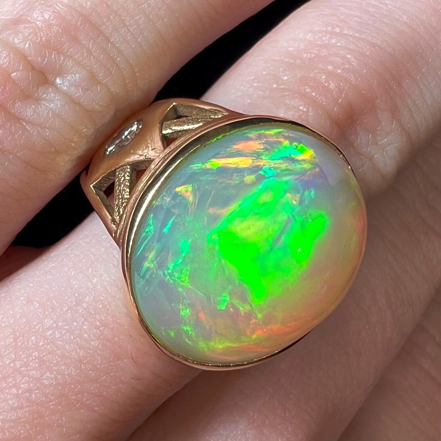 A custom yellow gold men's ring set with two diamonds and a large oval cabochon cut opal from Ethiopia, Africa.