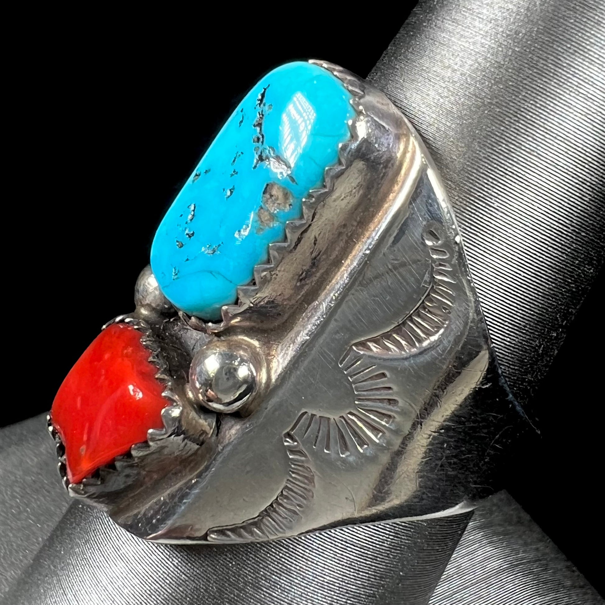 A men's sterling silver Navajo ring set with turquoise and red coral stones.