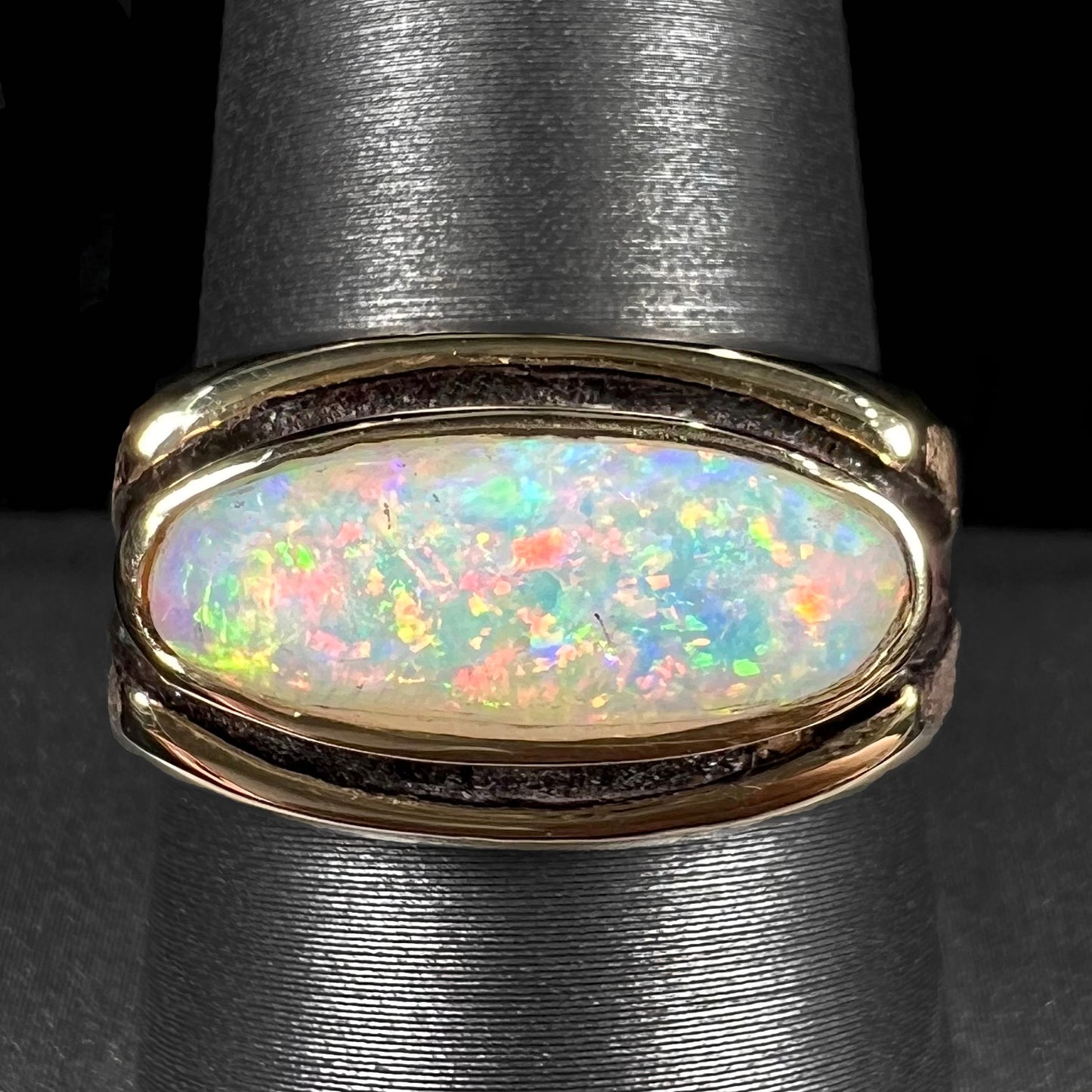 An Australian white crystal opal men's ring in solid yellow gold. The recesses of the ring have been blackened.