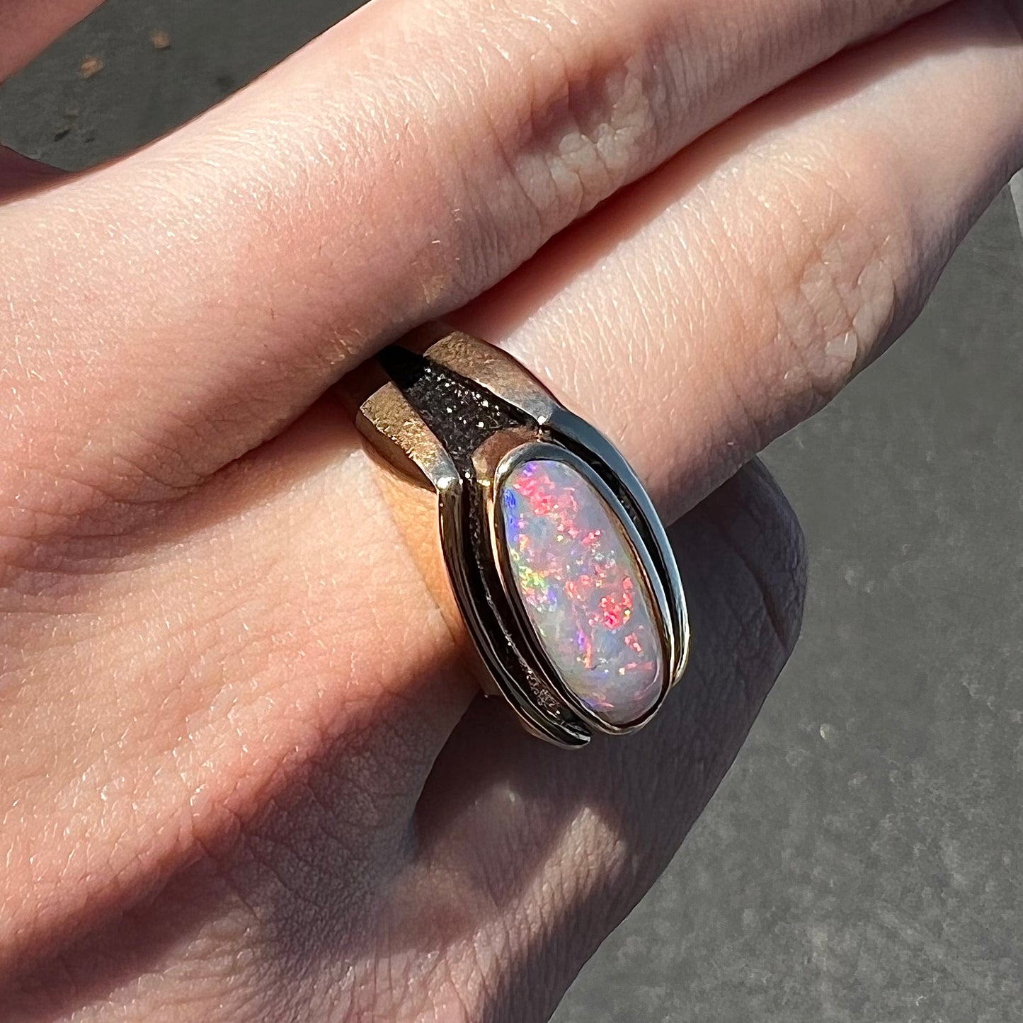 An Australian white crystal opal men's ring in solid yellow gold. The recesses of the ring have been blackened.