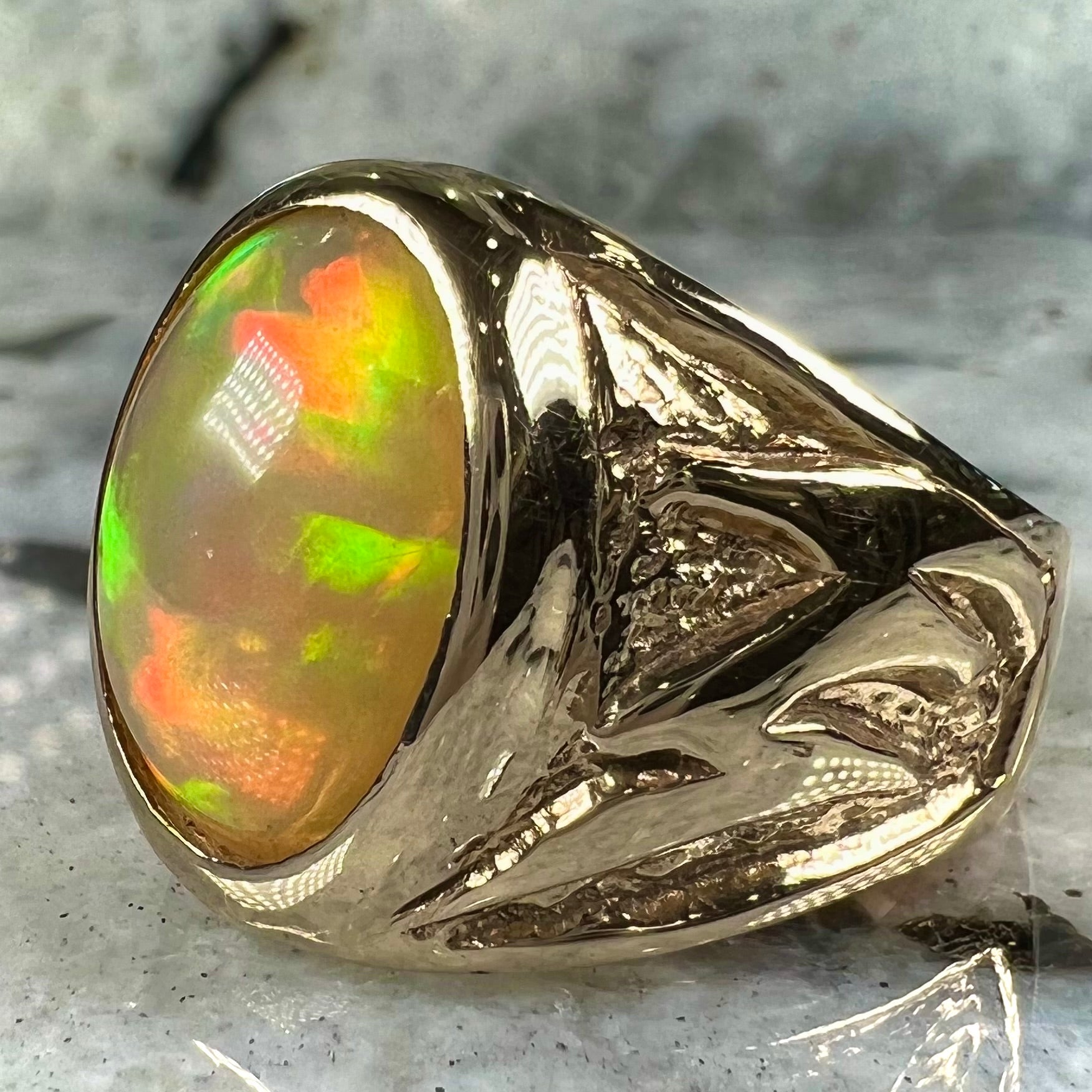 A solid yellow gold solitaire men's fire opal ring.  The stone is an orange oval cabochon cut.