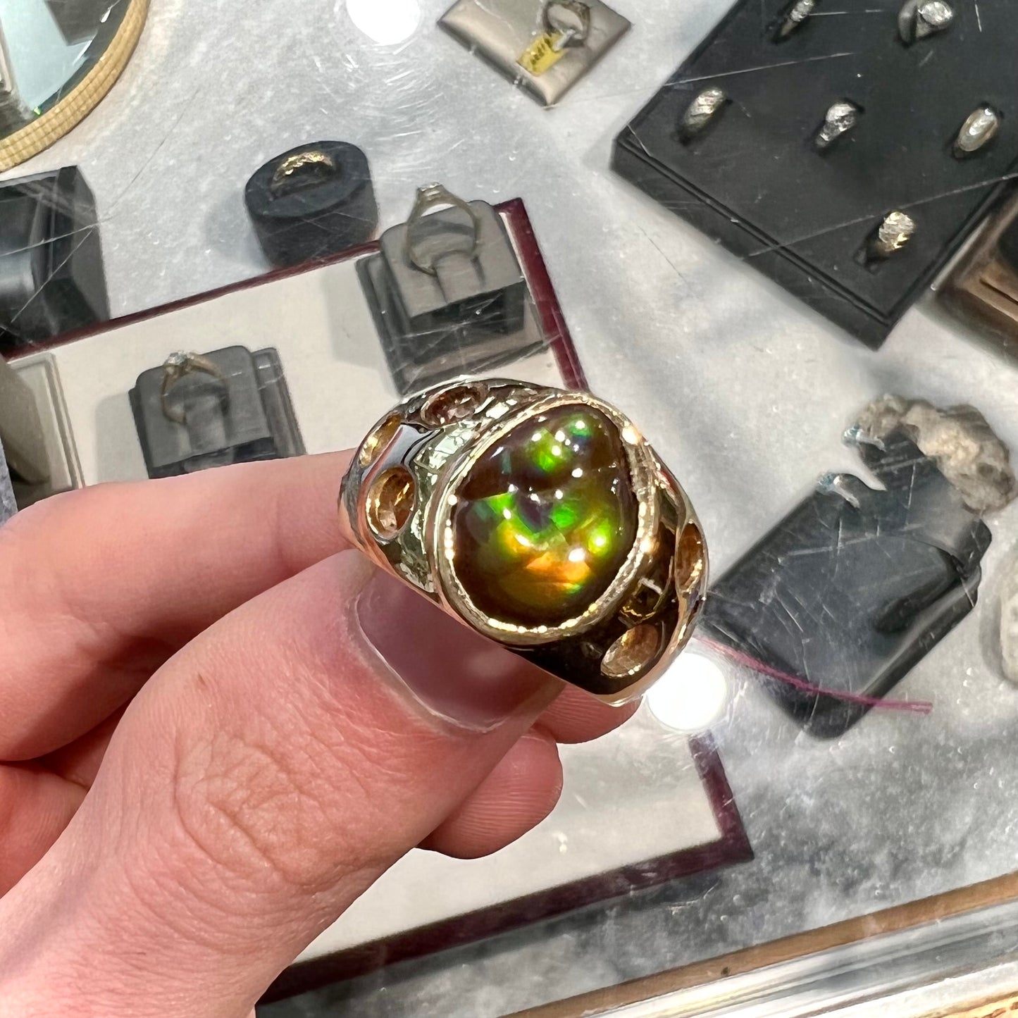 Men's rainbow fire agate ring set in yellow gold with champagne diamonds. The ring style has holes.