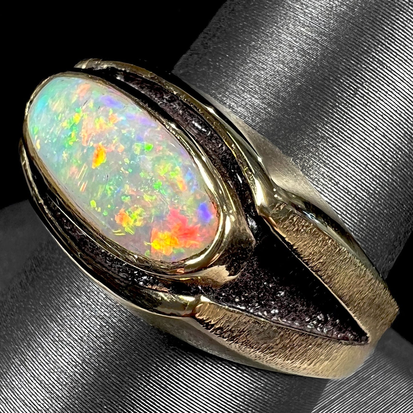 An Australian white crystal opal men's ring in solid yellow gold. The recesses of the ring have been blackened.