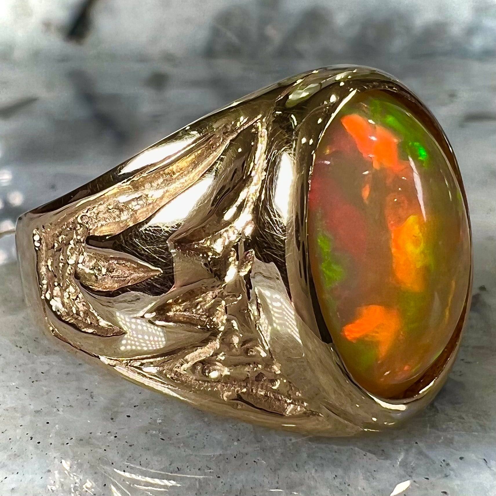 A solid yellow gold solitaire men's fire opal ring.  The stone is an orange oval cabochon cut.