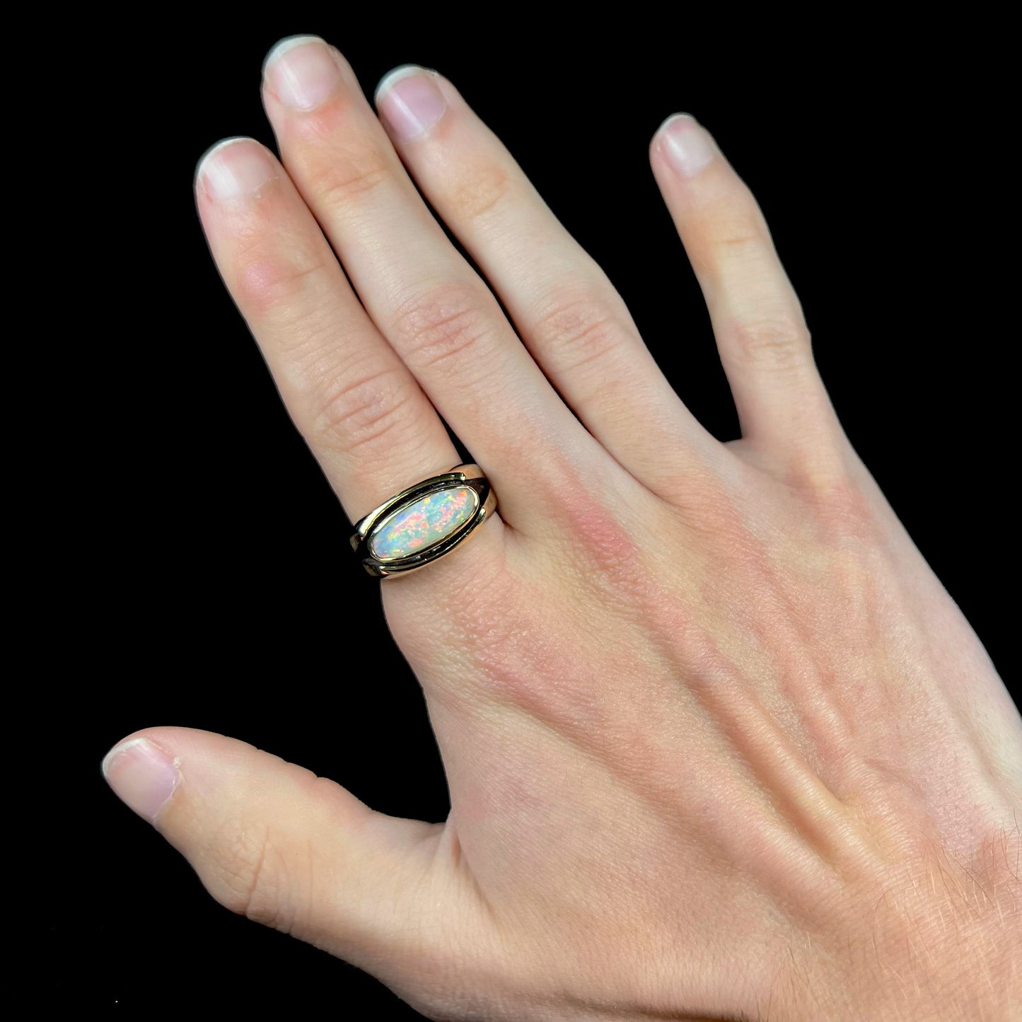 An Australian white crystal opal men's ring in solid yellow gold. The recesses of the ring have been blackened.