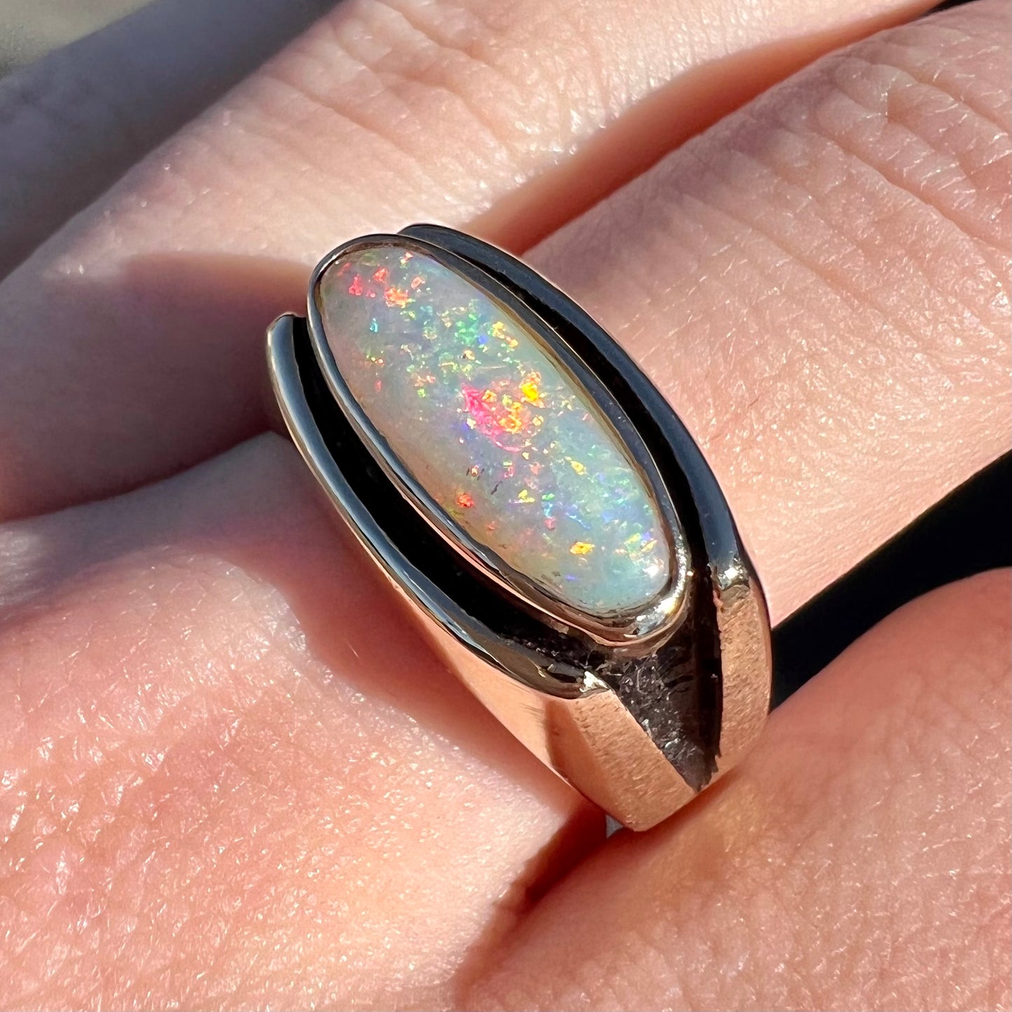 An Australian white crystal opal men's ring in solid yellow gold. The recesses of the ring have been blackened.