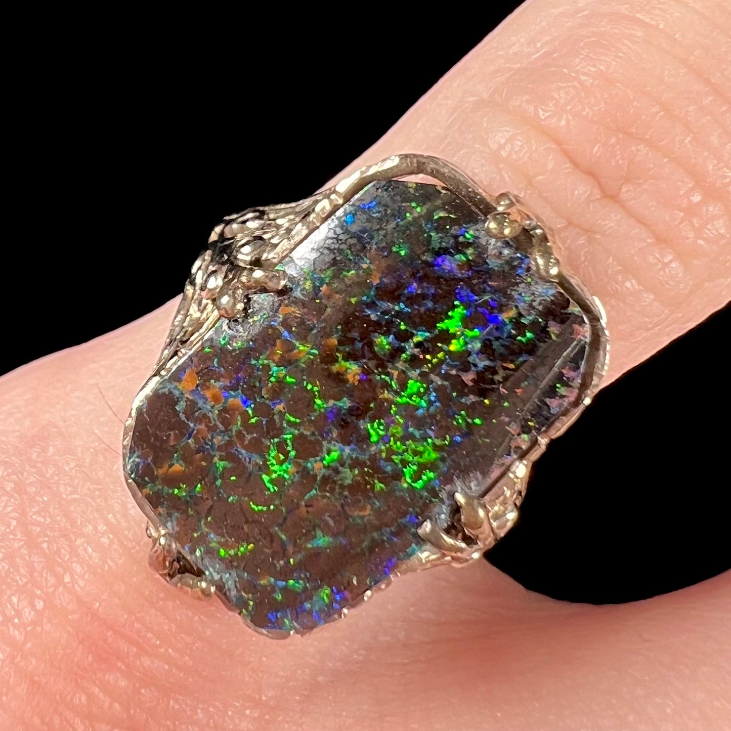 A vintage, white gold filigree unisex ring set with a natural black Koroit boulder opal.