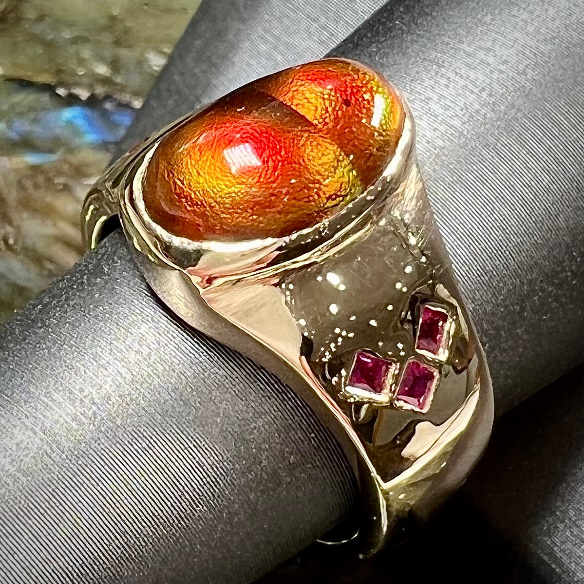 A yellow gold men's ring set with princess cut Burma rubies and a freeform cabochon cut red fire agate from Slaughter Mountain, Arizona.
