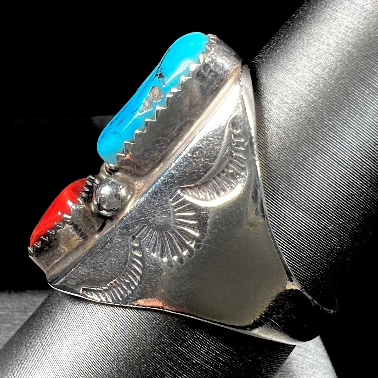 A men's sterling silver Navajo ring set with turquoise and red coral stones.