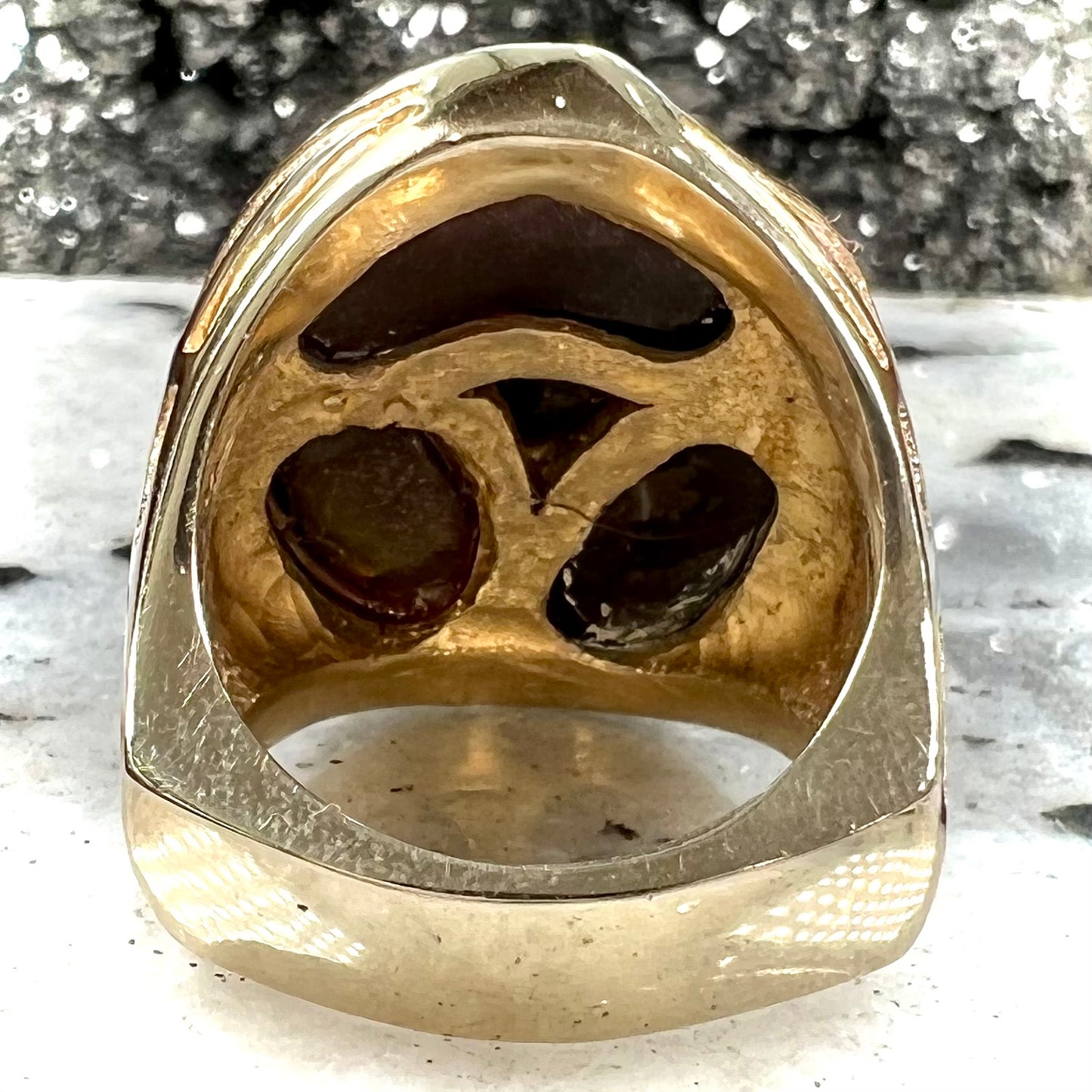 A yellow gold men's thug ring set with four fire agate stones resembling a spooky face.