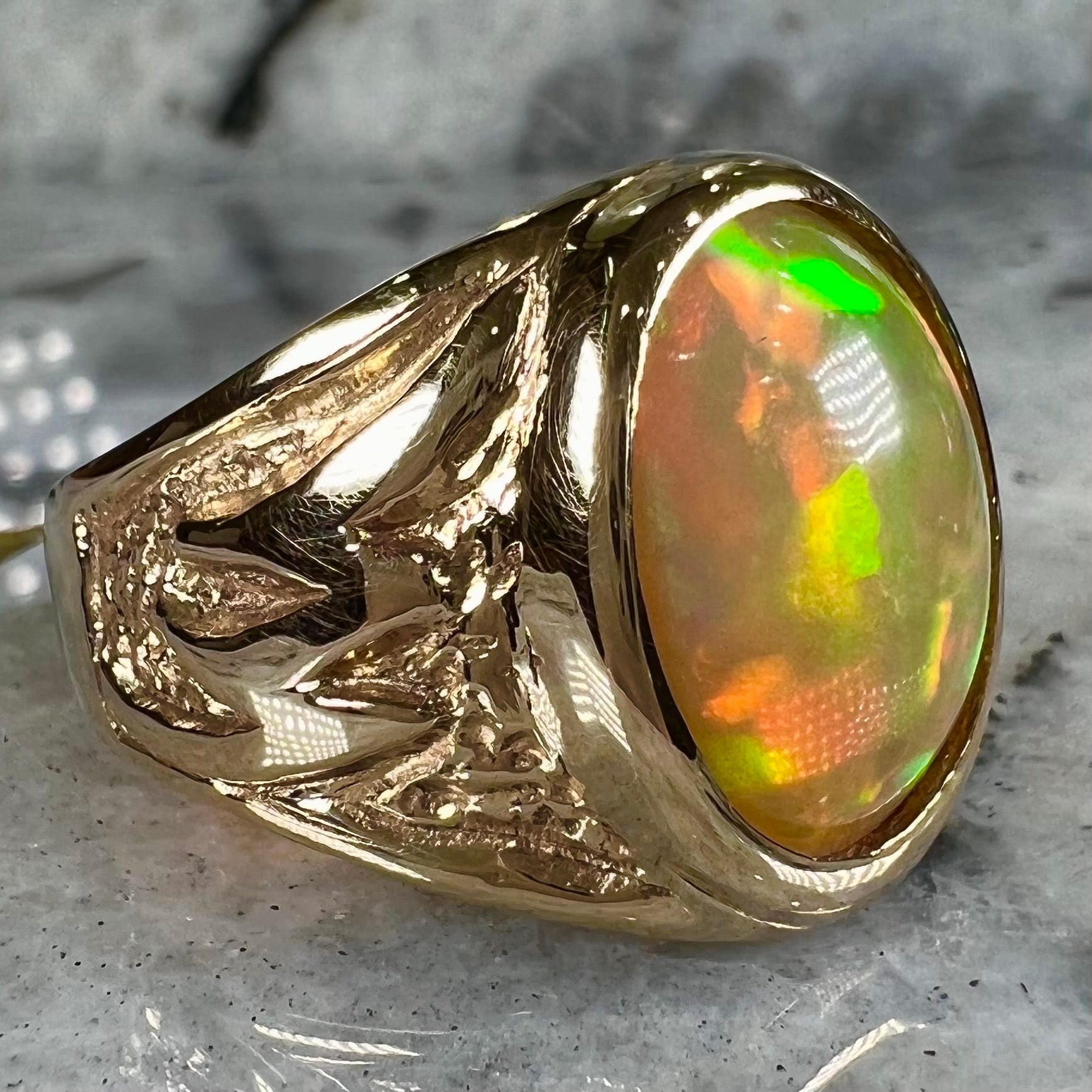 A solid yellow gold solitaire men's fire opal ring.  The stone is an orange oval cabochon cut.