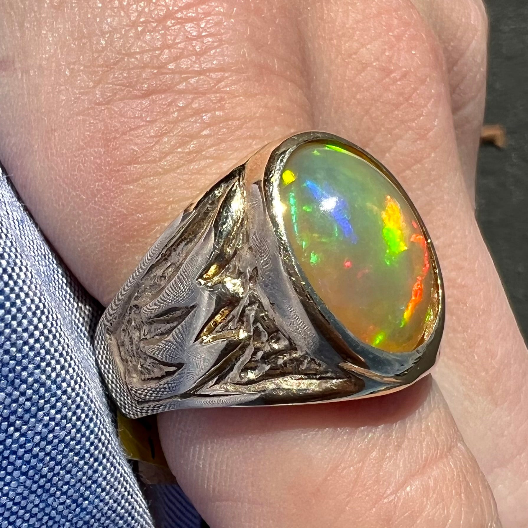 A solid yellow gold solitaire men's fire opal ring.  The stone is an orange oval cabochon cut.